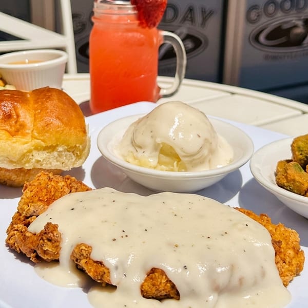 Chicken fried steak with gravy, mashed potatoes, fried okra, dinner roll, salad, and strawberry drink.